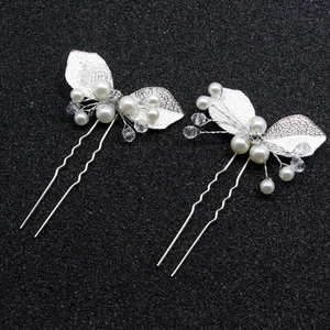 Détail d'épingles à cheveux feuilles argentées avec perles et cristaux sur fond noir