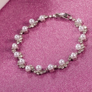 Dettaglio ravvicinato di un bracciale da sposa con perle bianche e strass scintillanti