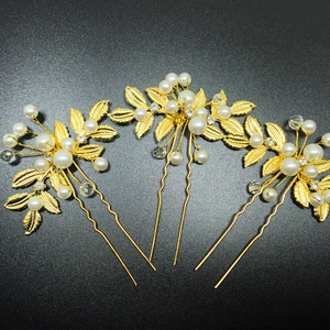 Macro d'épingles à cheveux dorées de mariée avec perles blanches et feuilles en métal doré