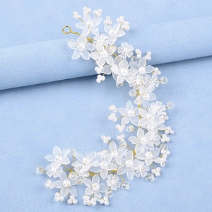 Détail d'un bandeau de mariée avec fleurs mates, perles blanches et fil doré torsadé