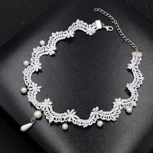 Elegante girocollo in pizzo bianco con ciondolo di perle su sfondo in pelle nera