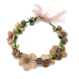 Detail of floral headpiece with faux pink roses, green leaves, and beige ribbon