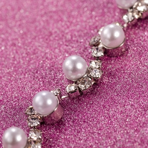 Dettaglio macro del bracciale da sposa con perle bianche e strass brillanti incastonati