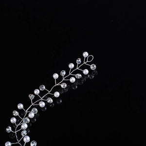 Detail of handmade silver bridal hair vine with pearls and faceted crystals on black background