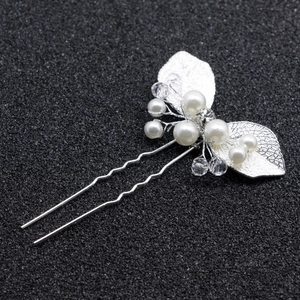 Détail d'une épingle à cheveux argentée avec perles blanches, cristaux et feuilles
