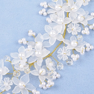 Détail d'un bijou de tête de mariée avec fleurs mates, perles et fil doré