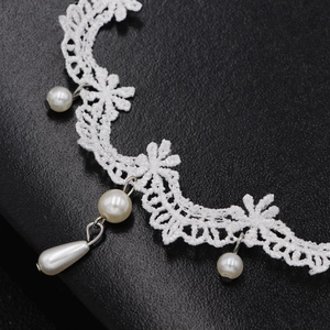 Choker in pizzo bianco con perle e motivo floreale su sfondo nero testurizzato