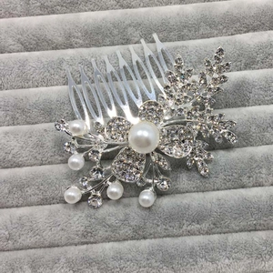 Détail macro du peigne de mariée avec perles et strass sur plateau en velours