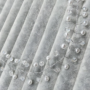 Detail of silver bridal hair vine with delicate pearls and clear crystal beads on grey fabric