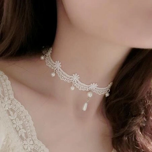 Vista dettagliata del girocollo in pizzo bianco con eleganti pendenti di perle sul collo