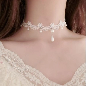 Dettaglio del choker in pizzo bianco con motivi floreali e pendente a perla elegante