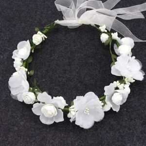Detail view of white fabric roses and green leaves on an adjustable floral headband