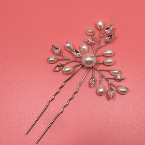 Close-up of handmade bridal hair pin with silver wire, white pearls and sparkling rhinestones