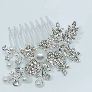 Détails d'un peigne de mariée argenté avec fleurs en cristal et perles blanches élégantes