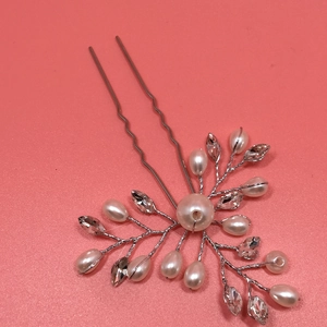 Detailed close-up of handmade bridal hair pin with pearls and crystals on pink background