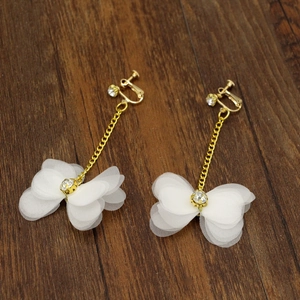 Détail de boucles d'oreilles pétales en tulle blanc avec chaînes dorées et strass