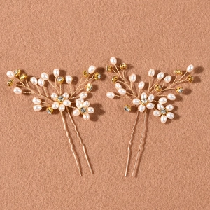 Detail of two handmade gold bridal hair pins with white pearls and sparkling crystals