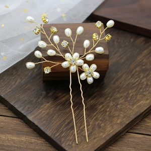 Detailed close-up of handmade bridal hair pin with pearls and crystals on golden wire