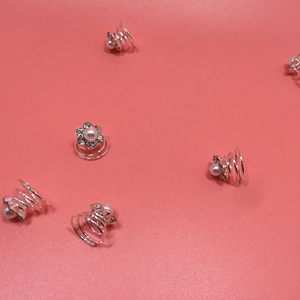 Gros plan d'épingles à cheveux spirales argentées avec perles et strass sur rose