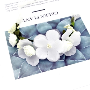 Close-up of white floral headband with fabric petals and green leaves for bridal hair