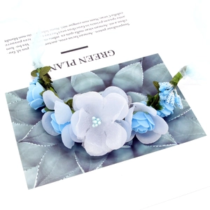 Detail of blue fabric flower crown with white beads and green vine base for weddings