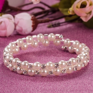 Detail of 6mm pearl and rhinestone double-layer stretch bracelet on pink floral background