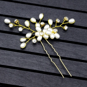 Close-up of handmade gold wire hair pin with pearls and crystals on a wood background