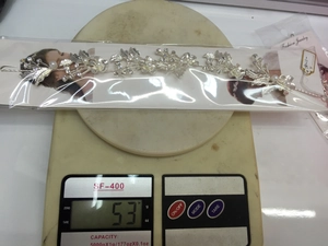 Detail shot of silver bridal headpiece with pearls and rhinestones on a weighing scale