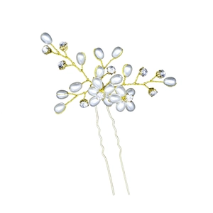 Close-up of handmade bridal hair pin with pearls and crystals on golden wire twigs