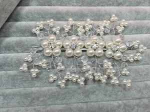 Detail view of bridal hair comb with pearls and crystals on grey velvet tray