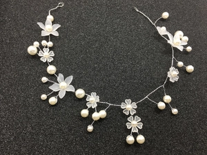 Macro detail of bridal hair vine with white frosted flowers and handmade pearls
