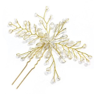 Detailed close-up of golden handmade bridal hair pin with crystal beads and floral branch