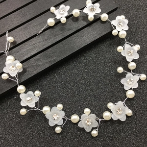 Détail d'une vigne de cheveux de mariée avec fleurs givrées, perles blanches et strass