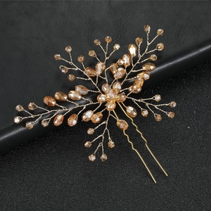 Detail of handmade gold bridal hair pin with amber crystal flowers and wire branch design