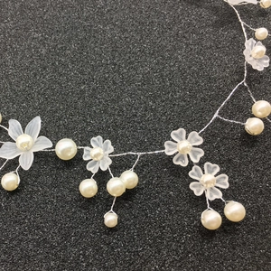 Close-up of handmade white frosted flower bridal headpiece with pearls and silver wire