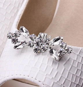 Close-up of sparkling crystal flower shoe buckle on white crocodile leather shoes