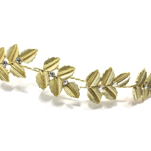 Macro view of gold bridal headband featuring textured metal leaves and sparkling rhinestones