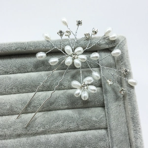 Close-up of handmade bridal hair pin with white pearls and sparkling crystal flowers