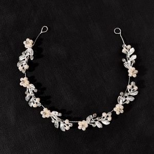Detailed view of bridal hair vine with silver leaves, faux pearls and crystals on black texture