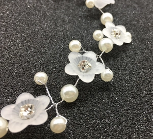 Détails macro d'un bandeau de mariée avec fleurs givrées, perles et cristaux de strass