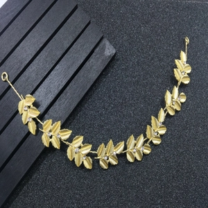 Detailed view of golden metal leaves and white rhinestones on bridal hairband accessory