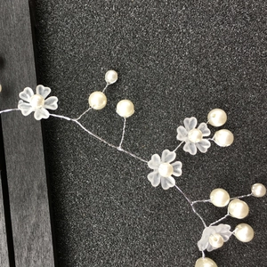 Detail of bridal headband featuring frosted flowers and white imitation pearls on silver wire