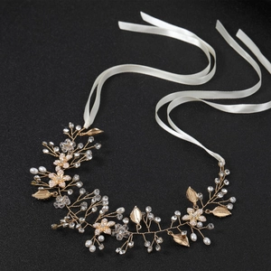 Accessorio per capelli da sposa con perle bianche e foglie d'oro su uno sfondo nero