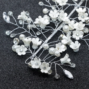 Détail macro du bandeau de mariée avec fleurs blanches, cristaux et perles sur sable noir
