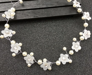 Détail d'une vigne de cheveux de mariée avec fleurs givrées et perles sur fond sombre
