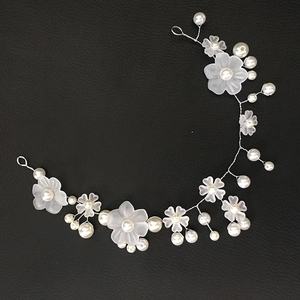 Handmade bridal hair vine with white matte flowers and pearls on a black background