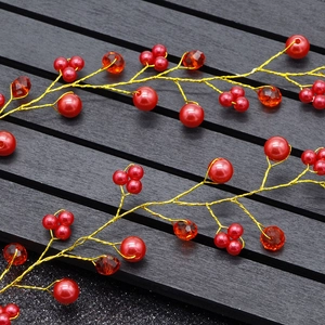 Detailed close-up of handmade red crystal and pearl bridal hair vine with golden wire