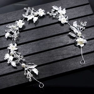 Detail of silver bridal headband featuring crystal flowers, leaves, and white pearls