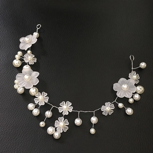 Detail of white matte flower bridal headband with handmade pearls on black leather background