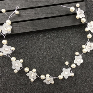 Vue détaillée d'un serre-tête de mariée artisanal avec fleurs en résine et perles